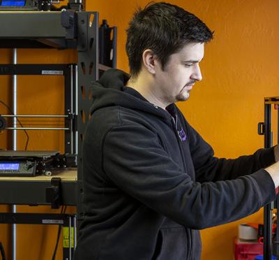 Bradley Heenk working on a 3D printer.