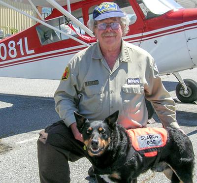 Bill Reed and his dog Scout posing in front of a small aircraft.