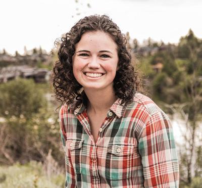 A student smiling in the middle of a field.