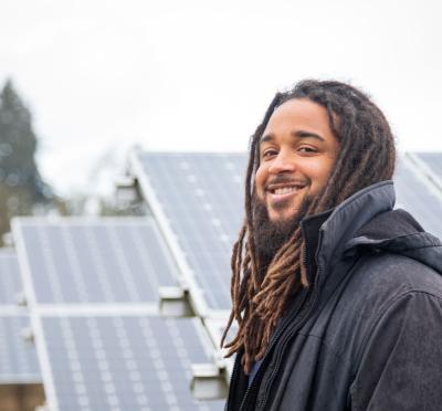 Portrait of Kyle Proctor in front of solar panels