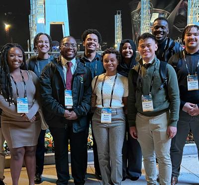 10 students standing shoulder-to-shoulder with each other for a group portrait wearing conference lanyards