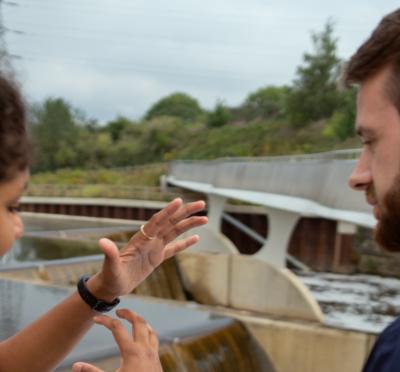 Two people holding a diagram at a dam.