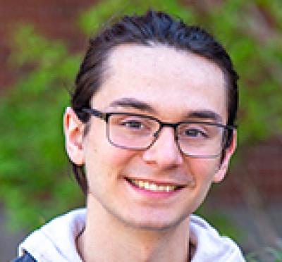 A student with glasses smiling at camera