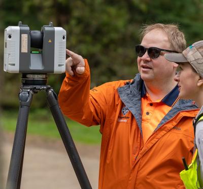 Two researchers look at 3D scanning instrument. 