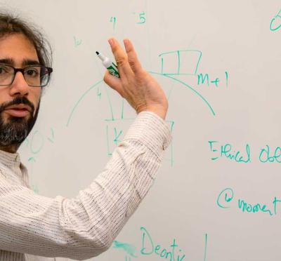 Oregon State Professor Houssam Abbas explaining engineering principles using on a whiteboard