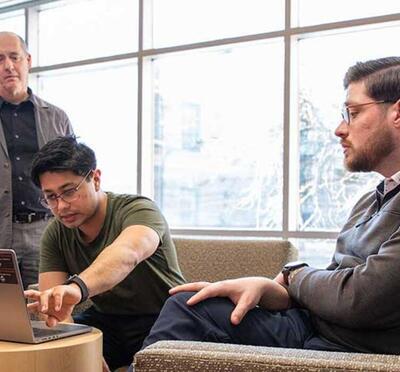 Group of people gathered around a laptop