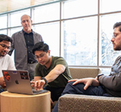 Group of people gathered around a laptop