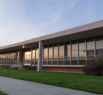 A campus building at sunset with reflections in the windows.