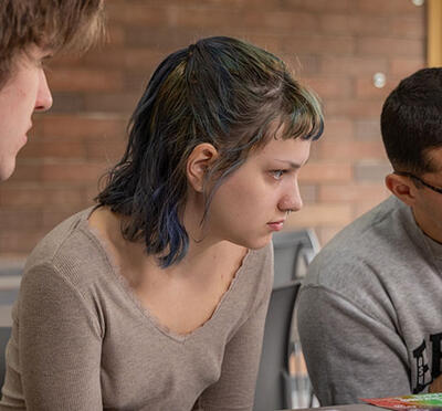 Three students looking at a computer screen inquisitively. 