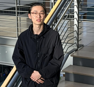 A person stands on stairs inside a contemporary office building with natural light shining on them. 