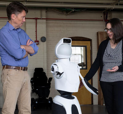 Two researchers standing with a robot.