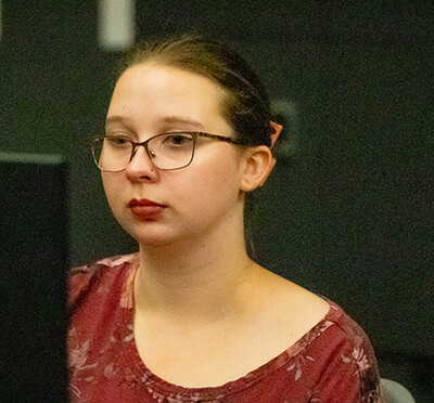Kyla Daskalos, wearing a red shirt, looks at a computer screen.