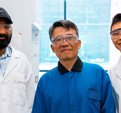 Venkata Vinay Doddapaneni, Chih-hung Chang, and Alvin Chang stand in a lab in Johnson Hall wearing lab coats and protective eyeglasses.