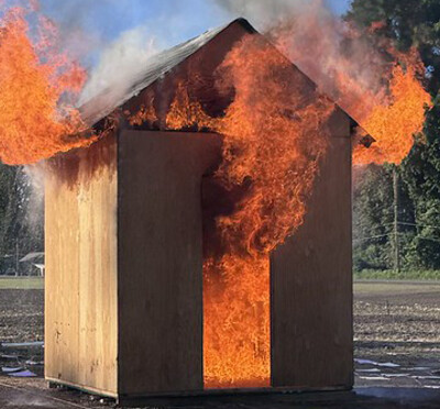 A small wooden hut that is on fire.