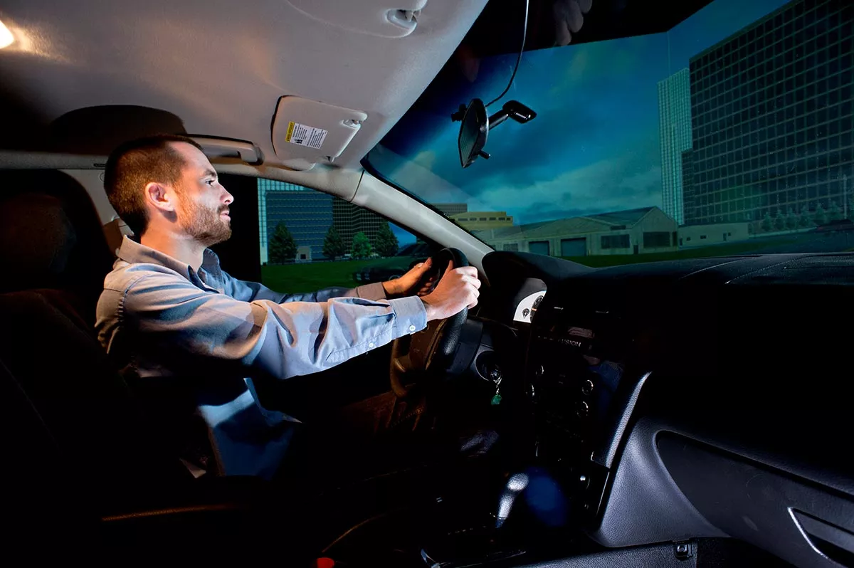 A person holding the car wheel about to drive in a car simulation. 