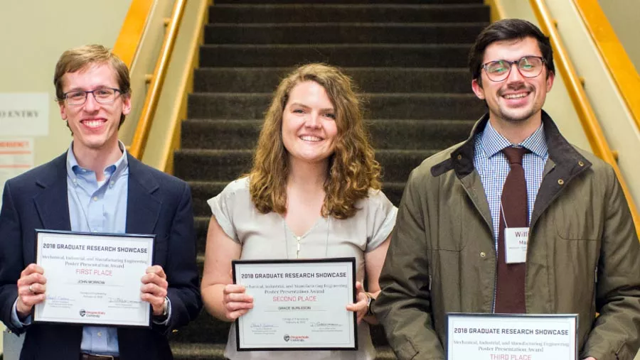 Three mechanical engineer students standing together with awards at the Graduate Research Showcase.