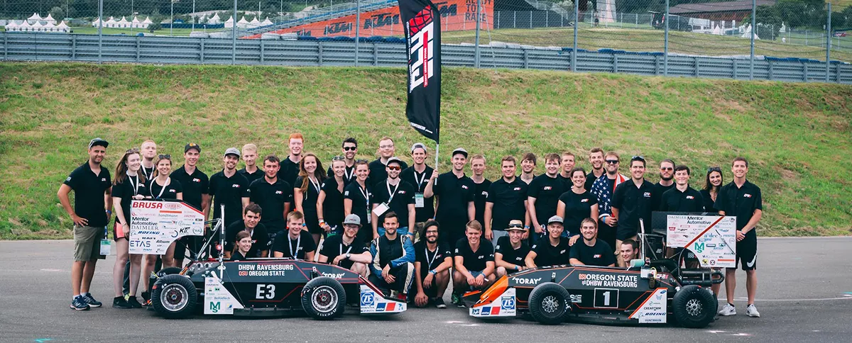 Students gathered around two small race cars.