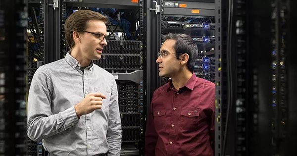 Two faculty members talking to each other in a room with servers. 