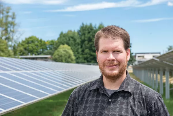 Chad Higgins standing next to solar panels.