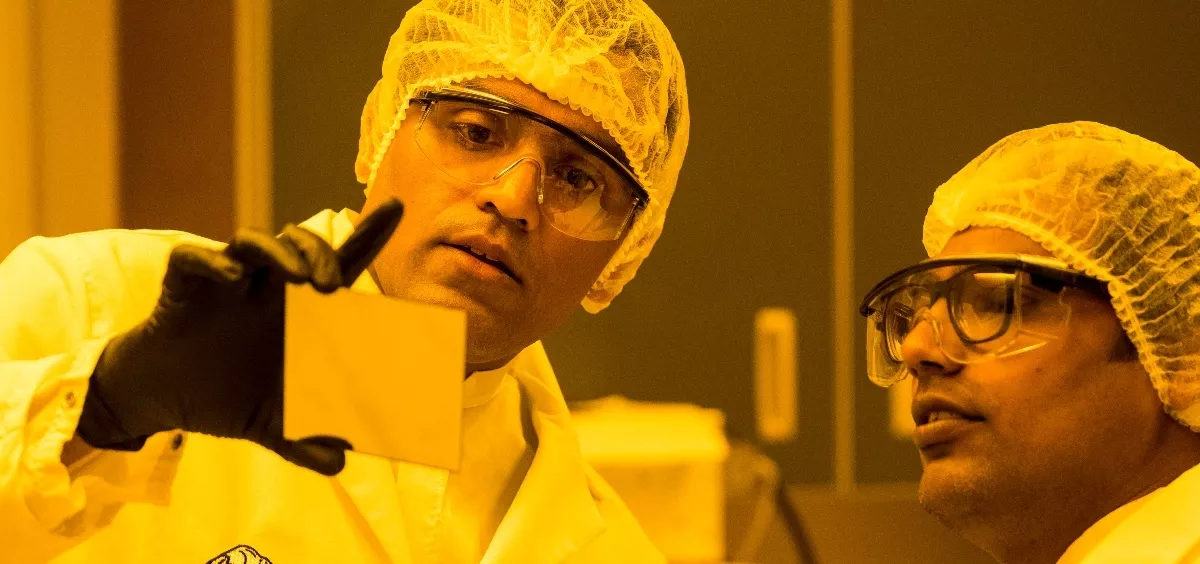 Two engineers in lab uniform examining an item