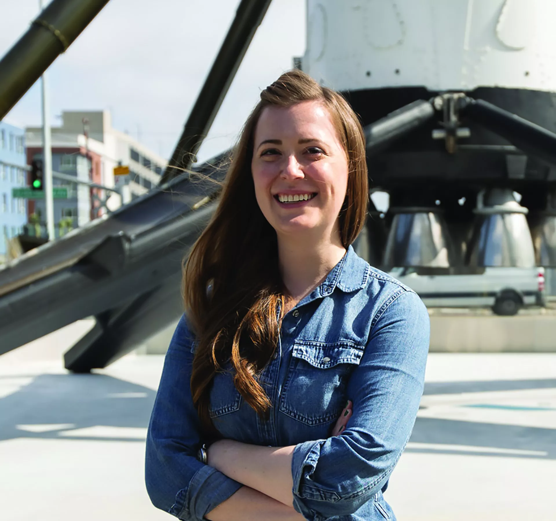 Jill Lewis standing outdoors in front of spaceship.