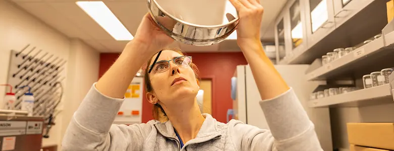 A person examining a metal bowl closely.