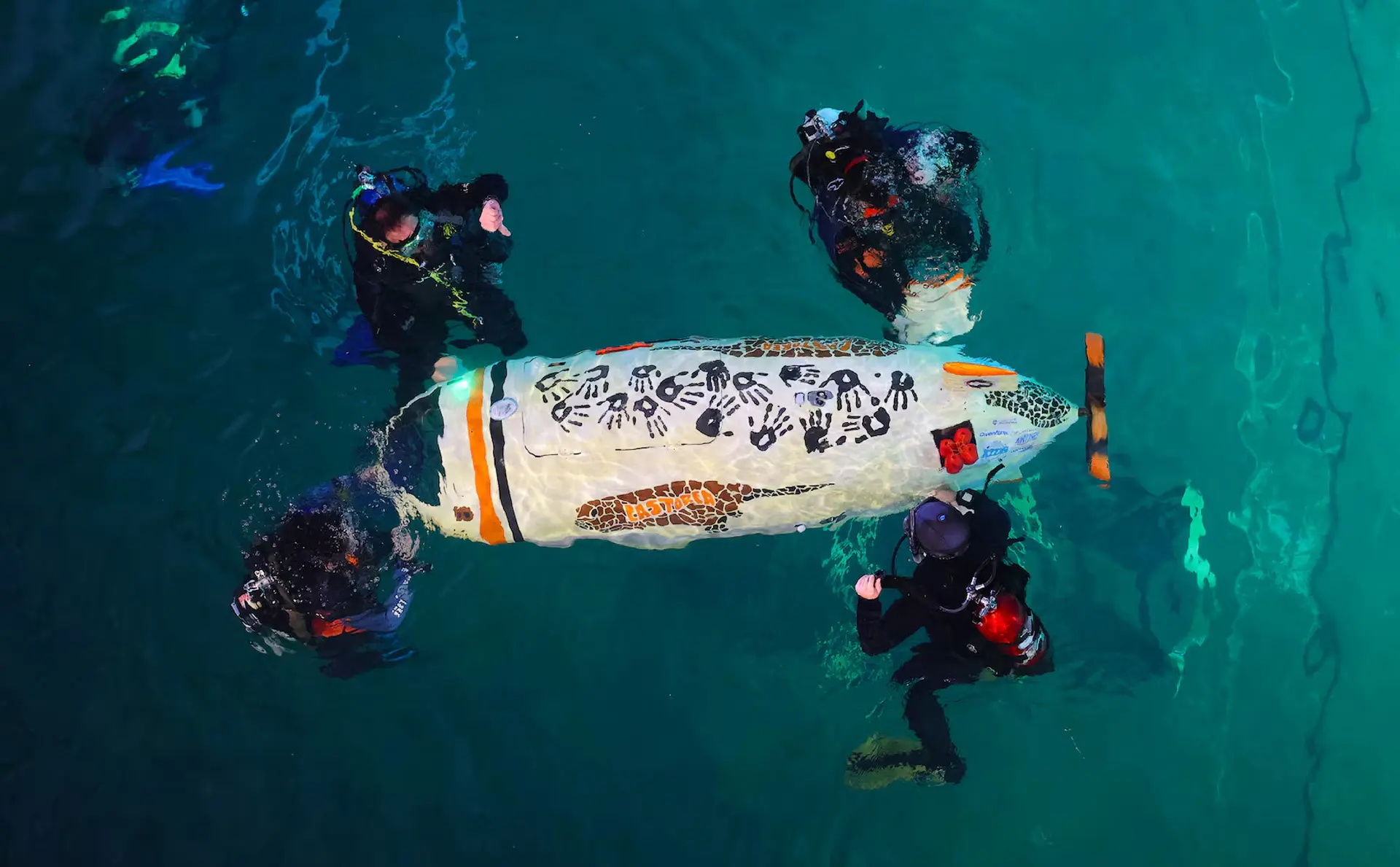 Four divers in a pool testing equipment