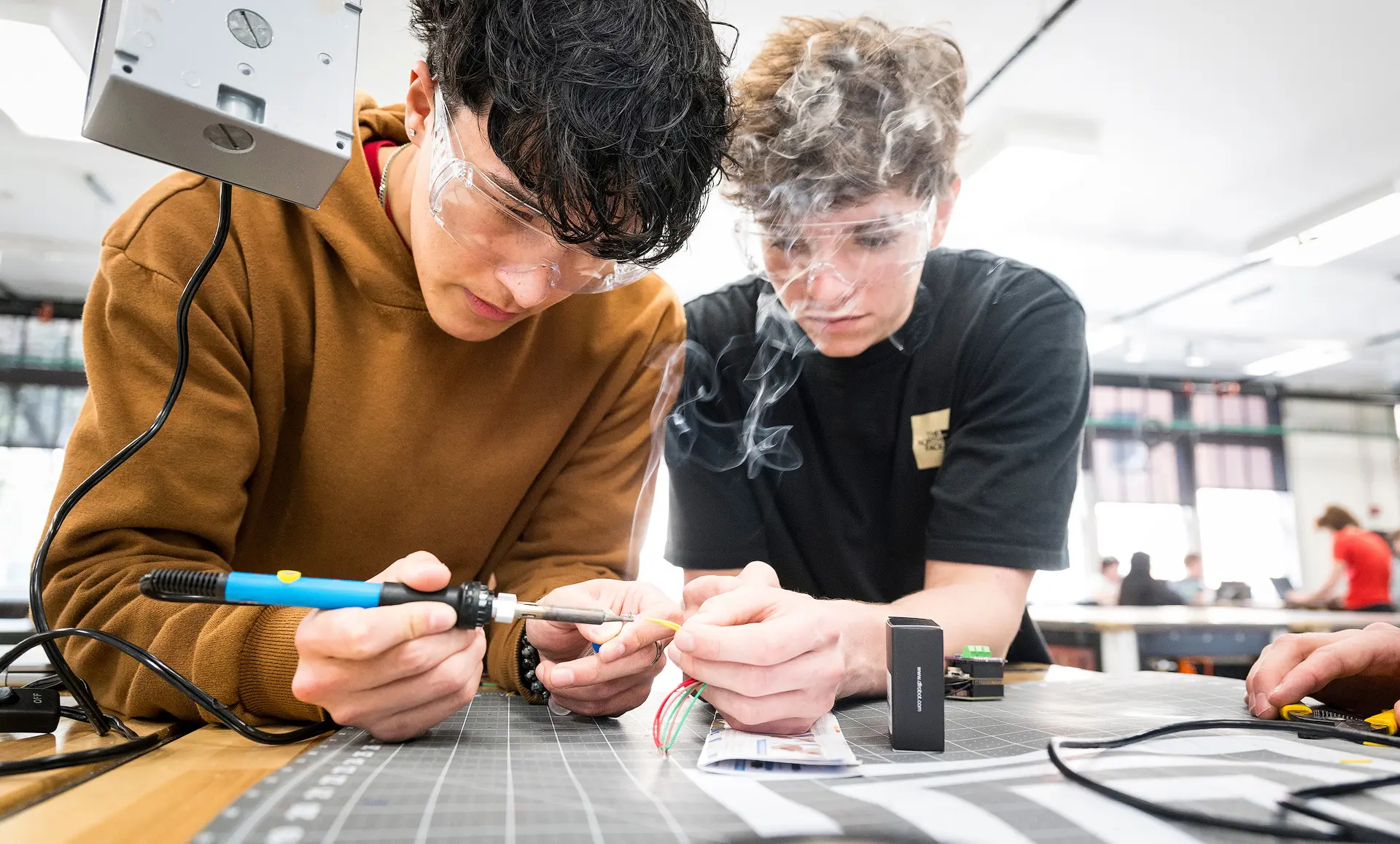 Two students soldering wires