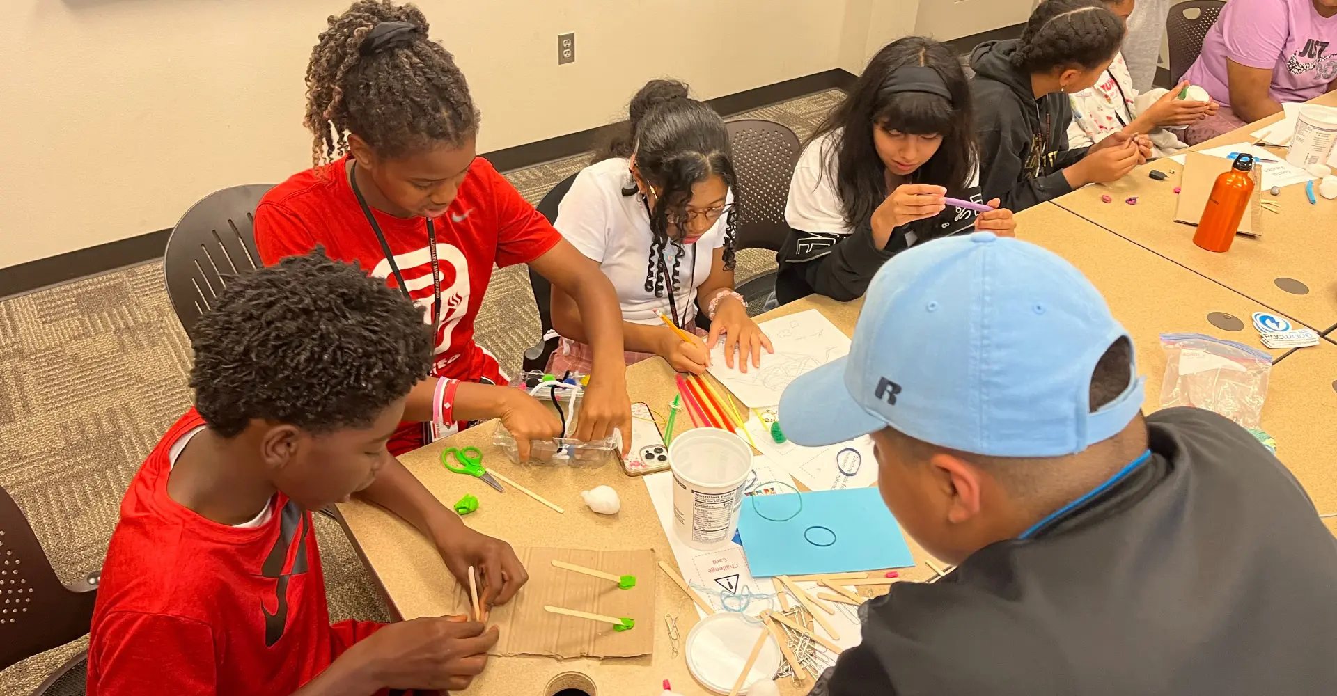 Children sitting at a desk making crafts.