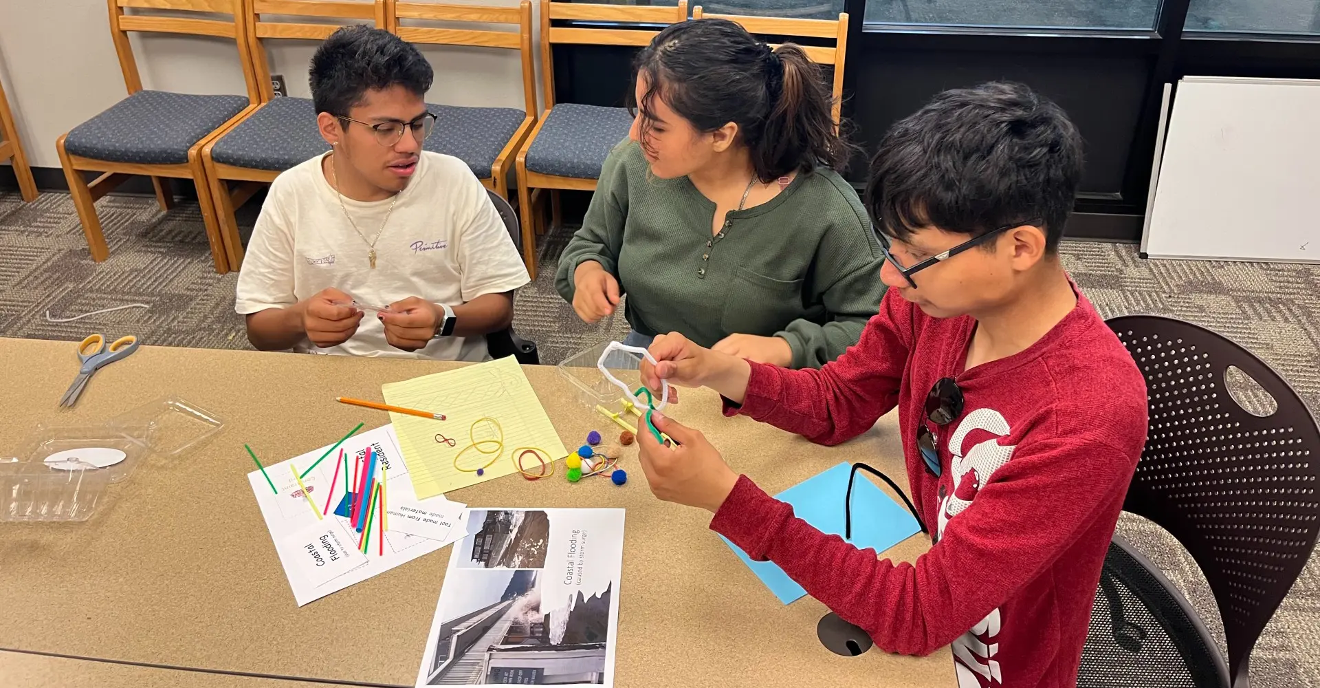 Two students working on crafts with a teacher.