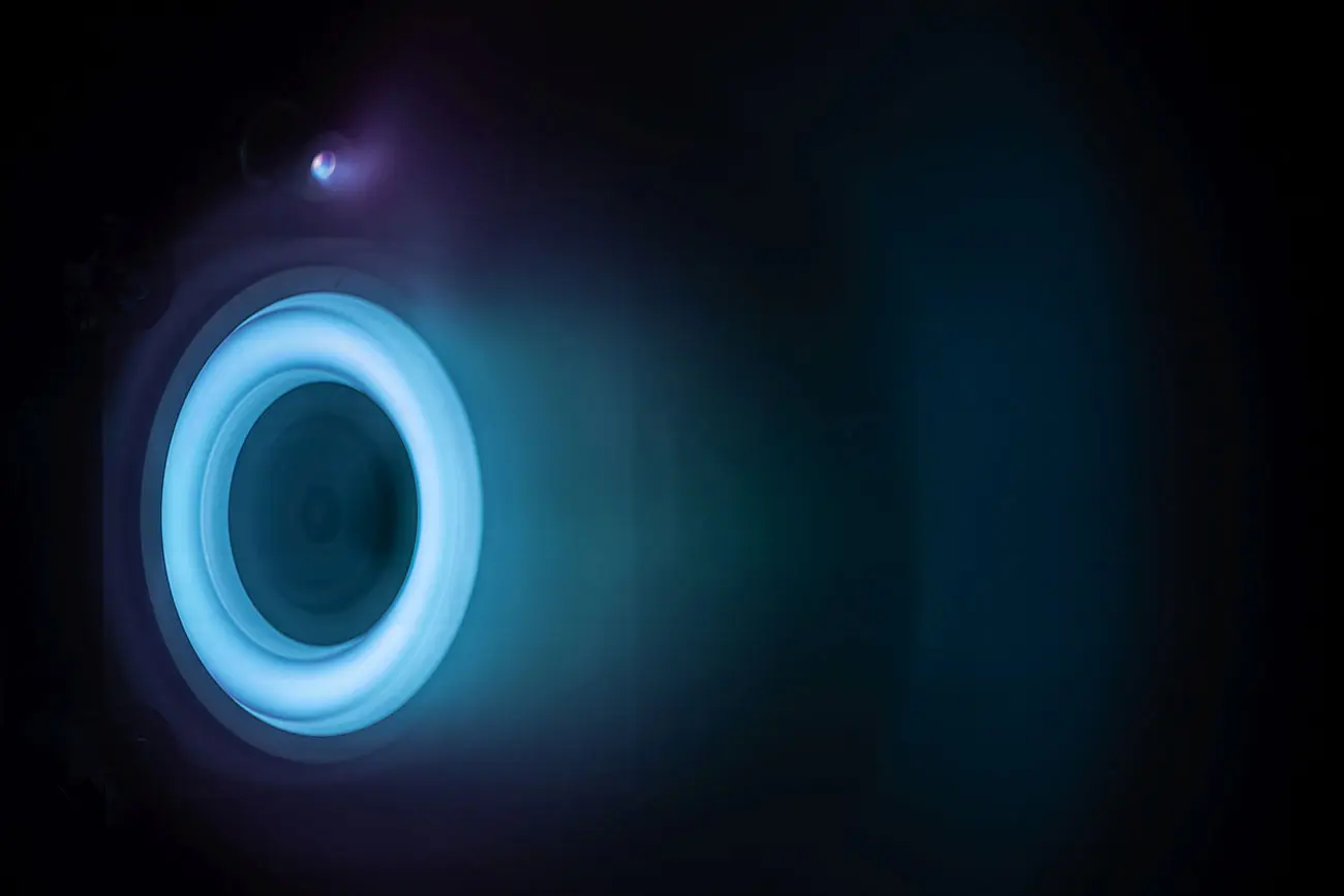 Rocket engine thruster glows with a blue ring of light.