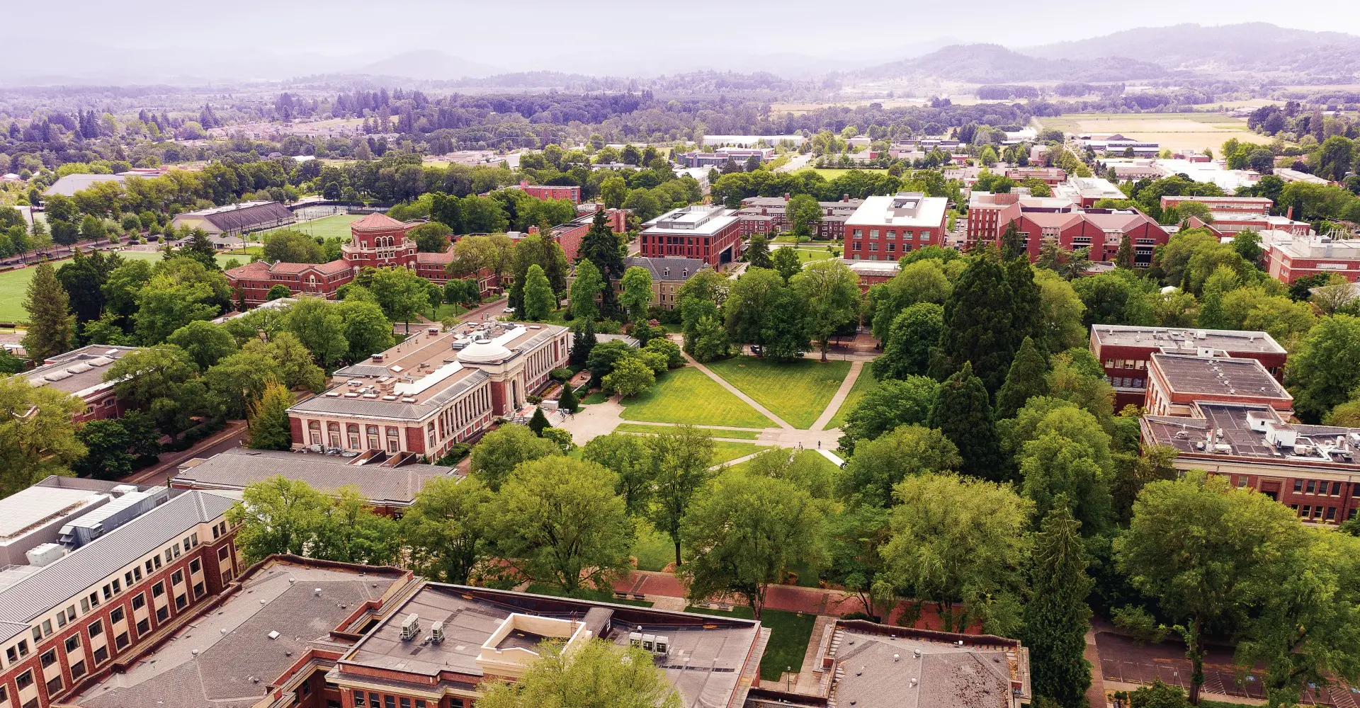 Aerial view of Oregon State University Campus with green trees and red brick buildings.
