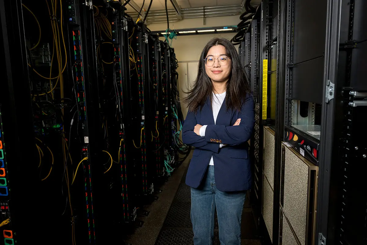 Wenqian Dong standing between racks of computer servers.