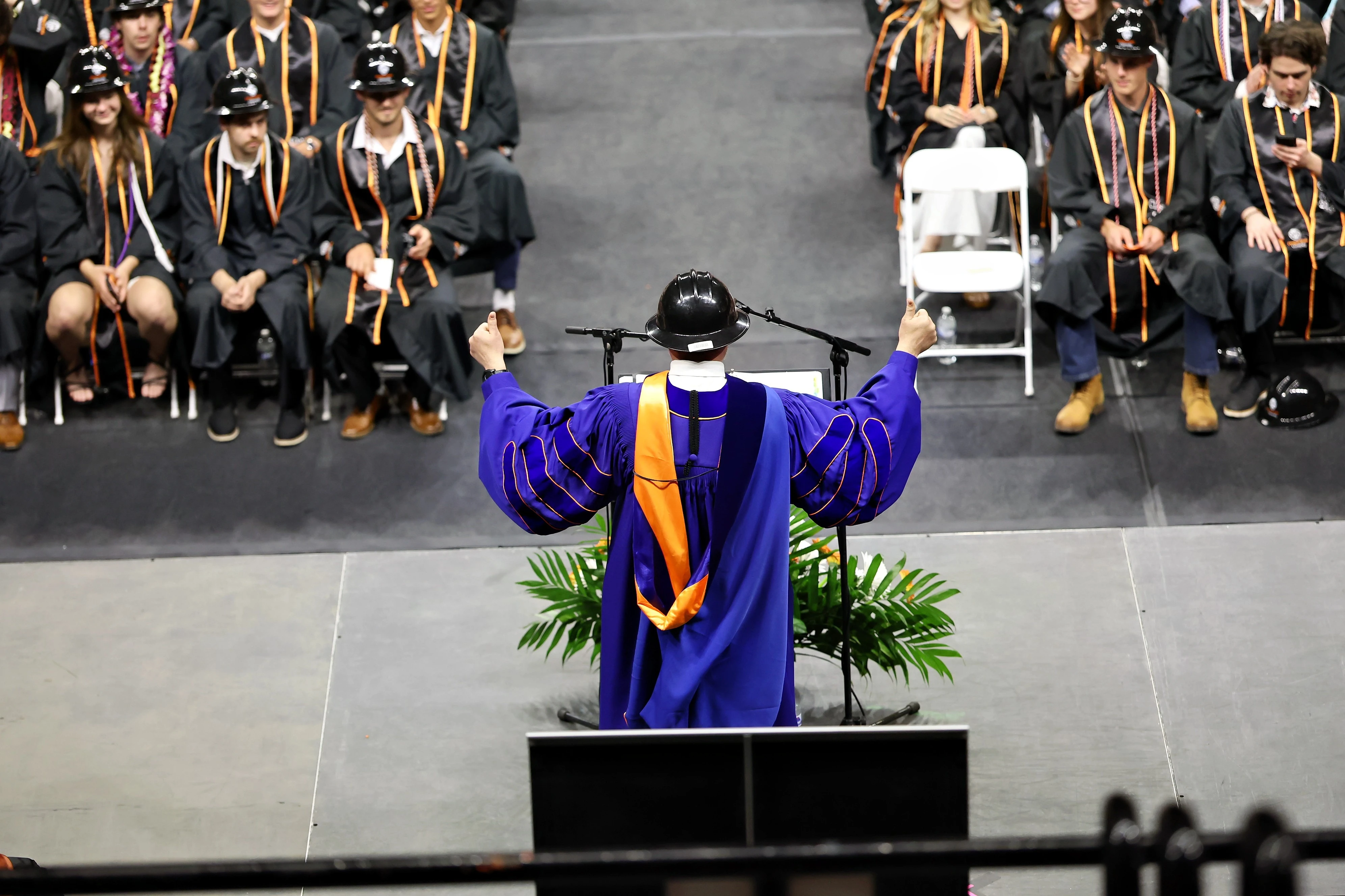 Oregon State University Civil and Construction engineering students wearing black gowns and hard hats at graduation.