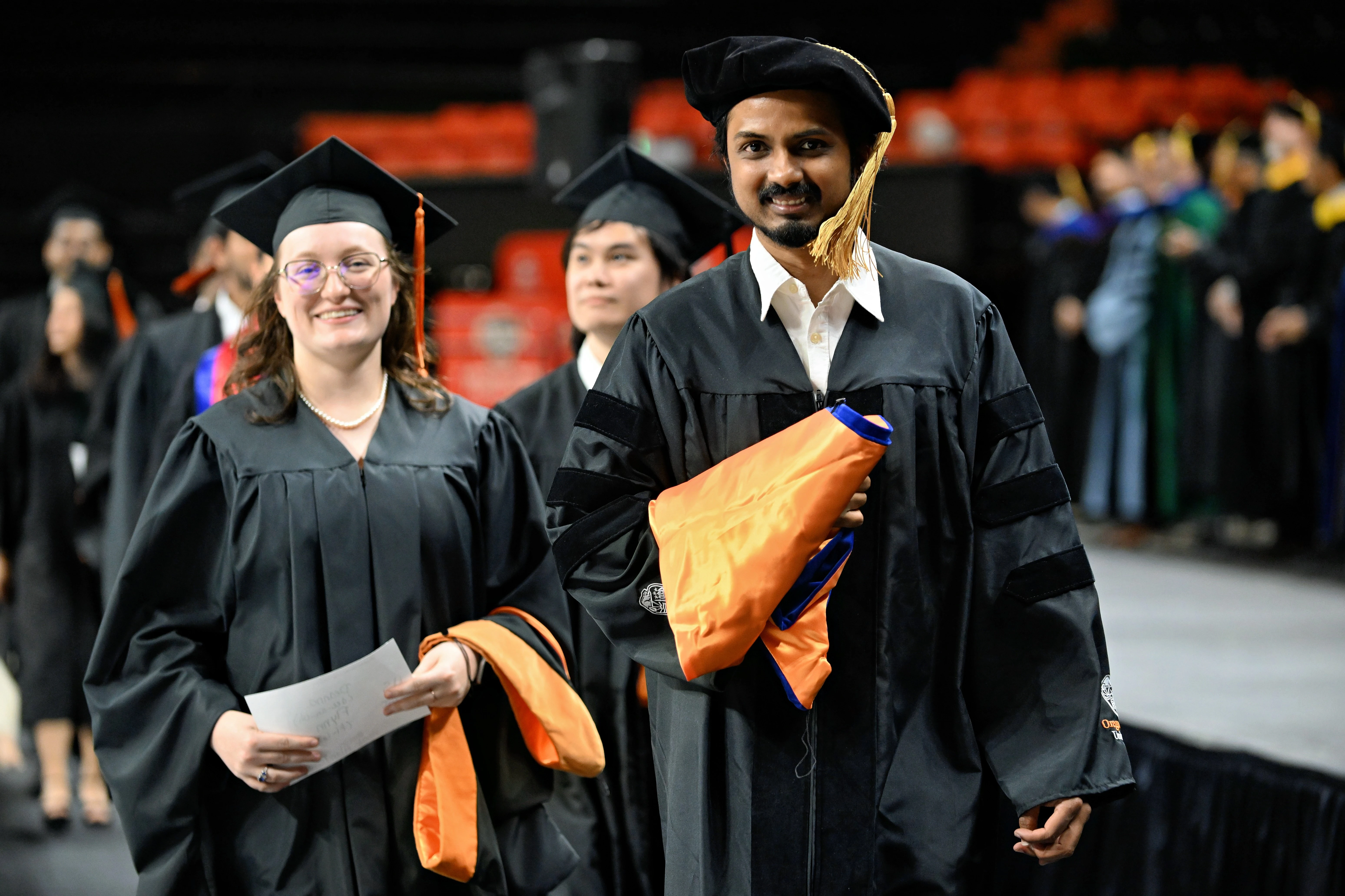 Oregon State University students wearing black gowns and caps at graduation.