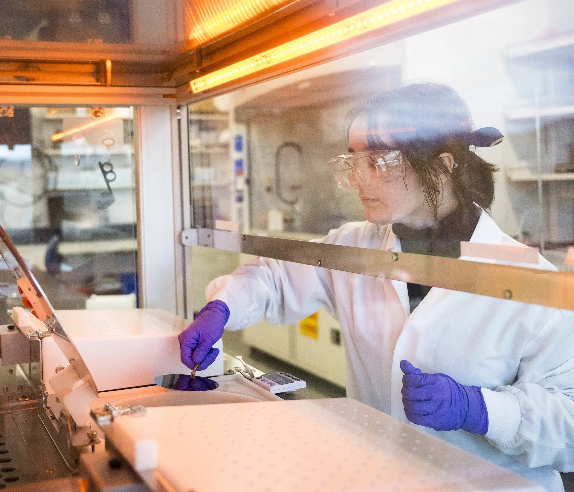 A lab researcher inspecting an item thru a glass.