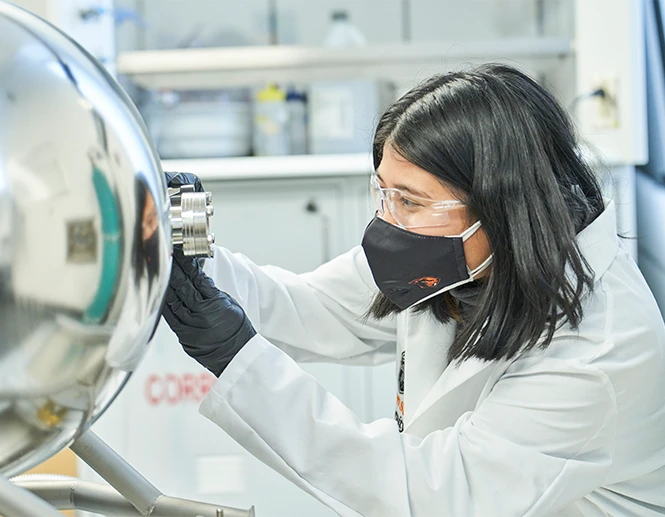 Student working in a lab with a mask on.