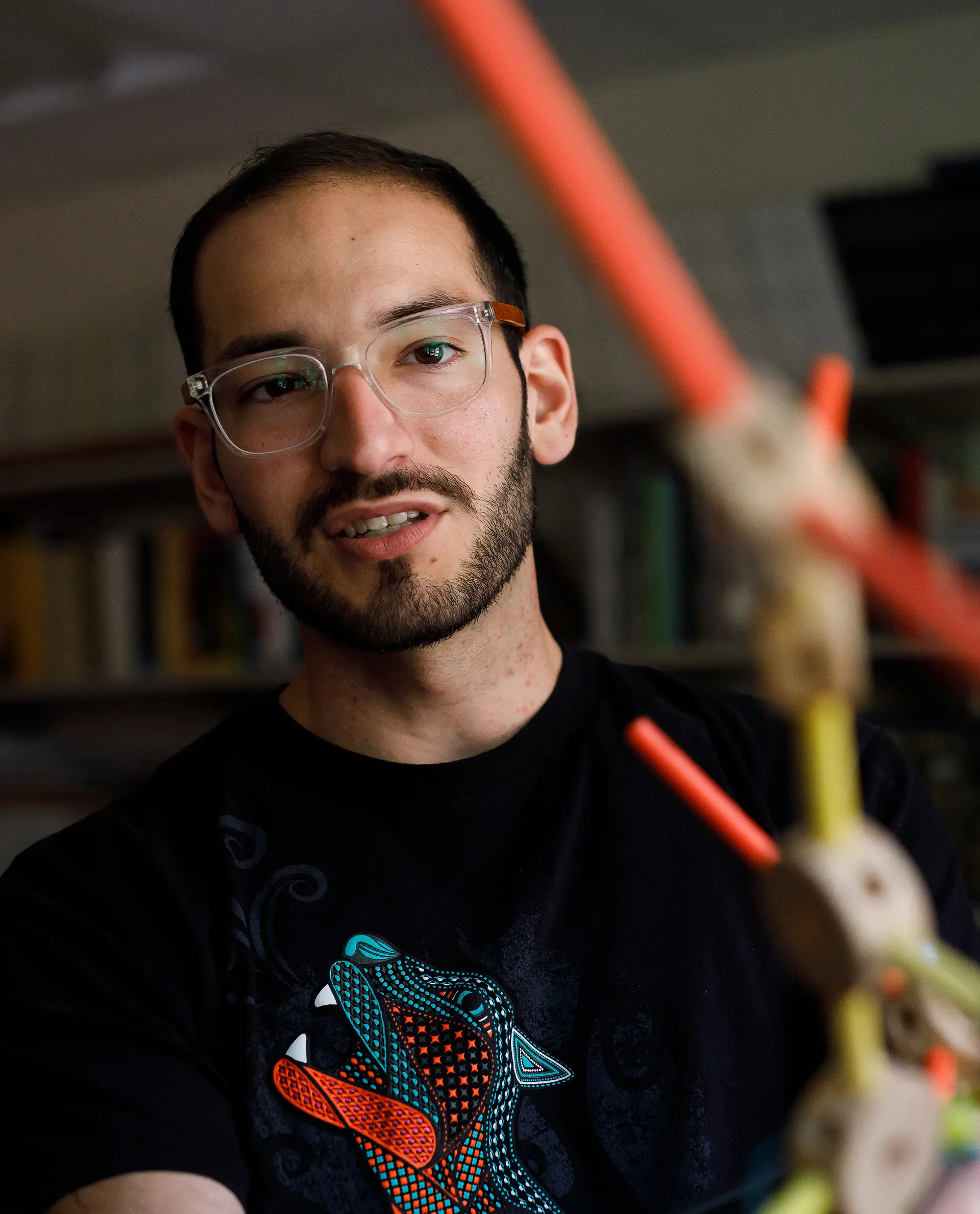 Engineering student looking at a structural model with orange and yellow arms.