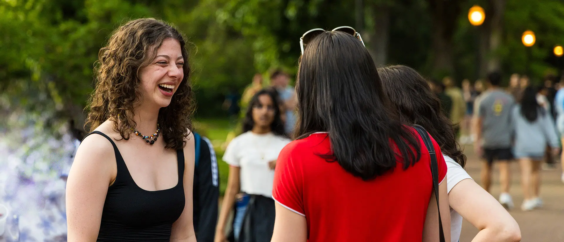 Engineering students talking and laughing in a street with a lush green background.