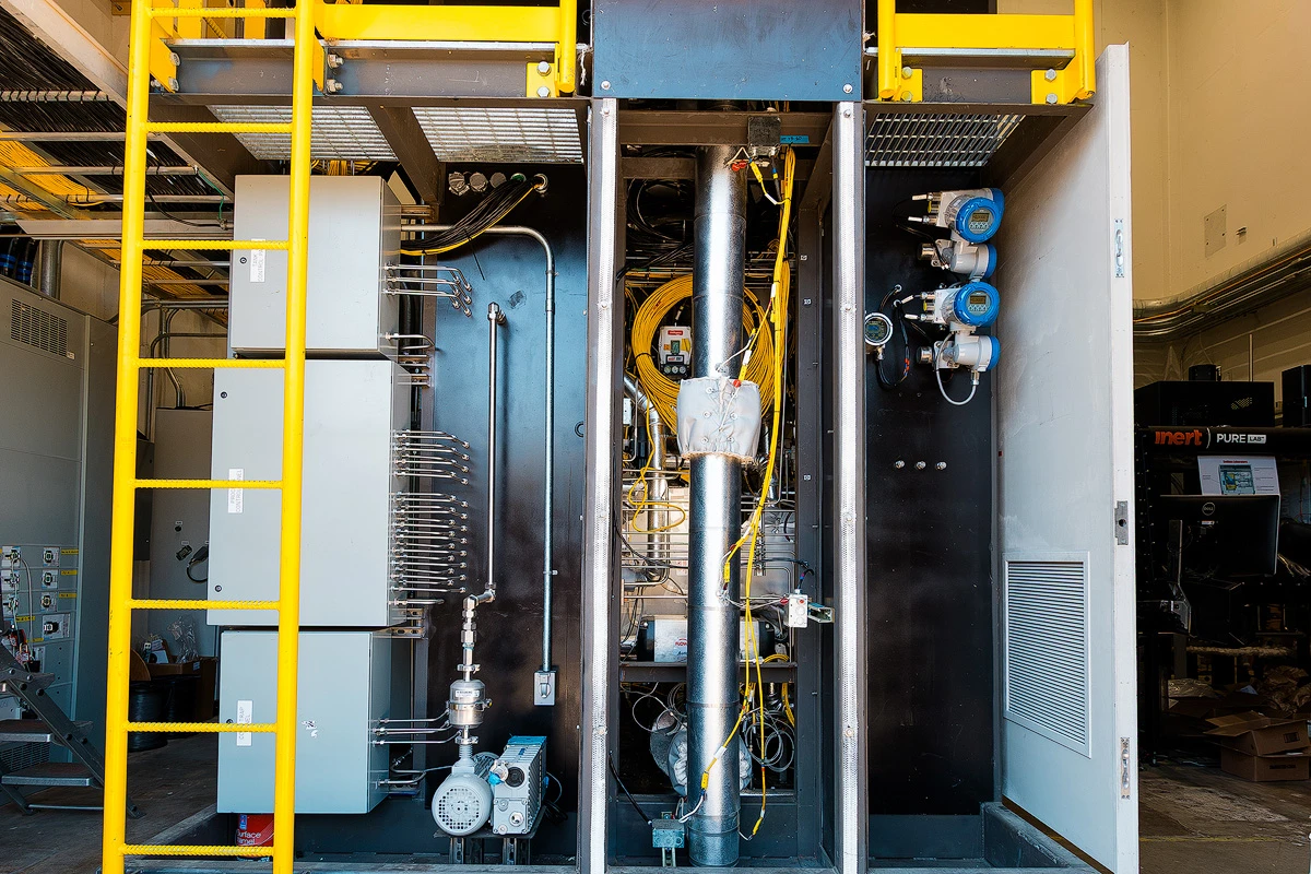 Side view of large facility filled with pipes, cables, valves, and metal components.