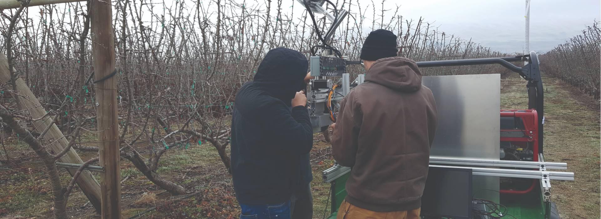 Two people working on a robot at a farm.