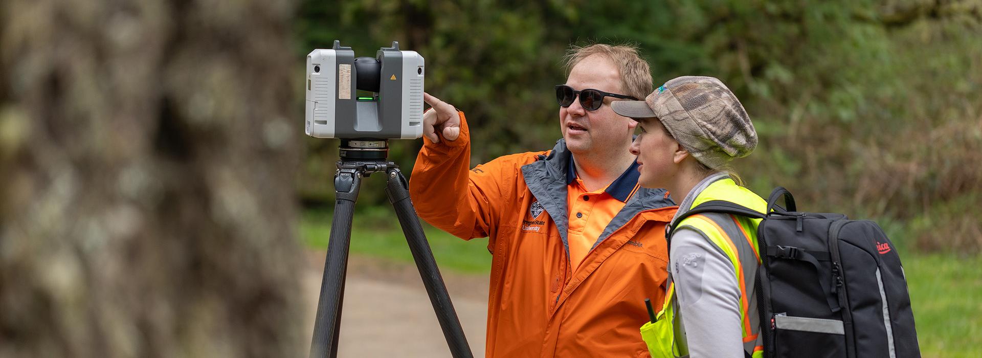 Two researchers look at 3D scanning instrument. 