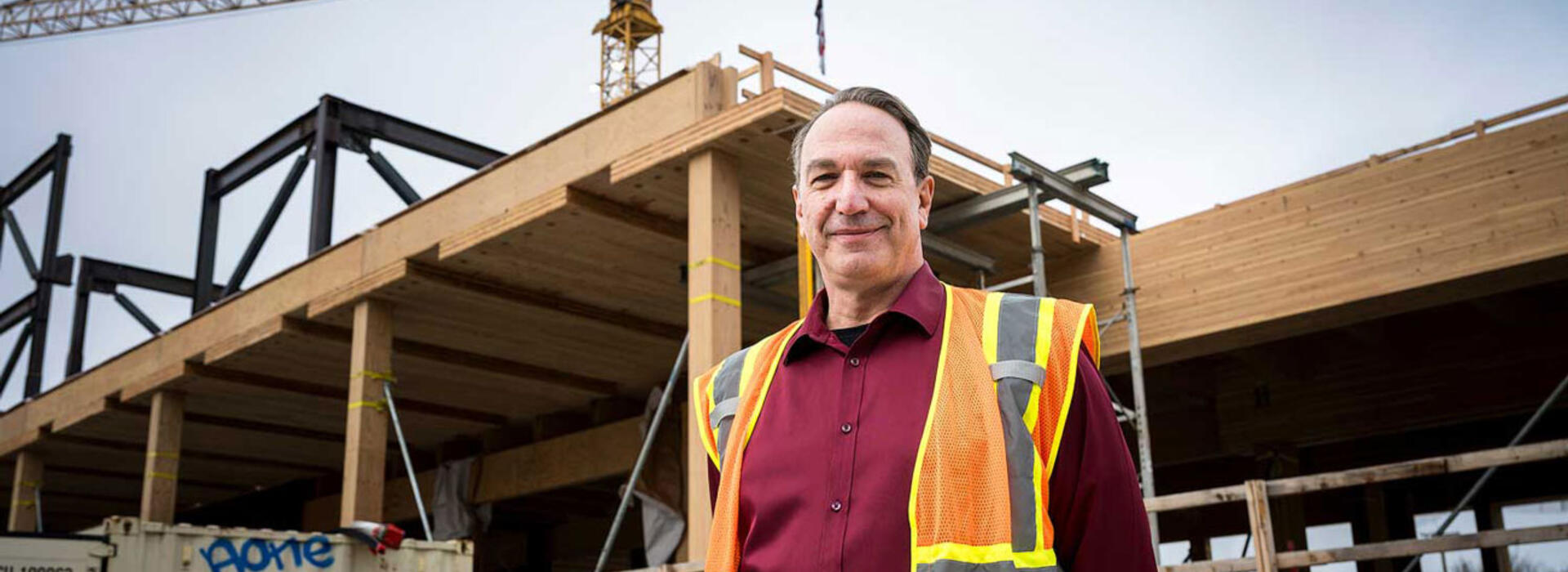 A person in personal protective equipment standing in front of a construction site.