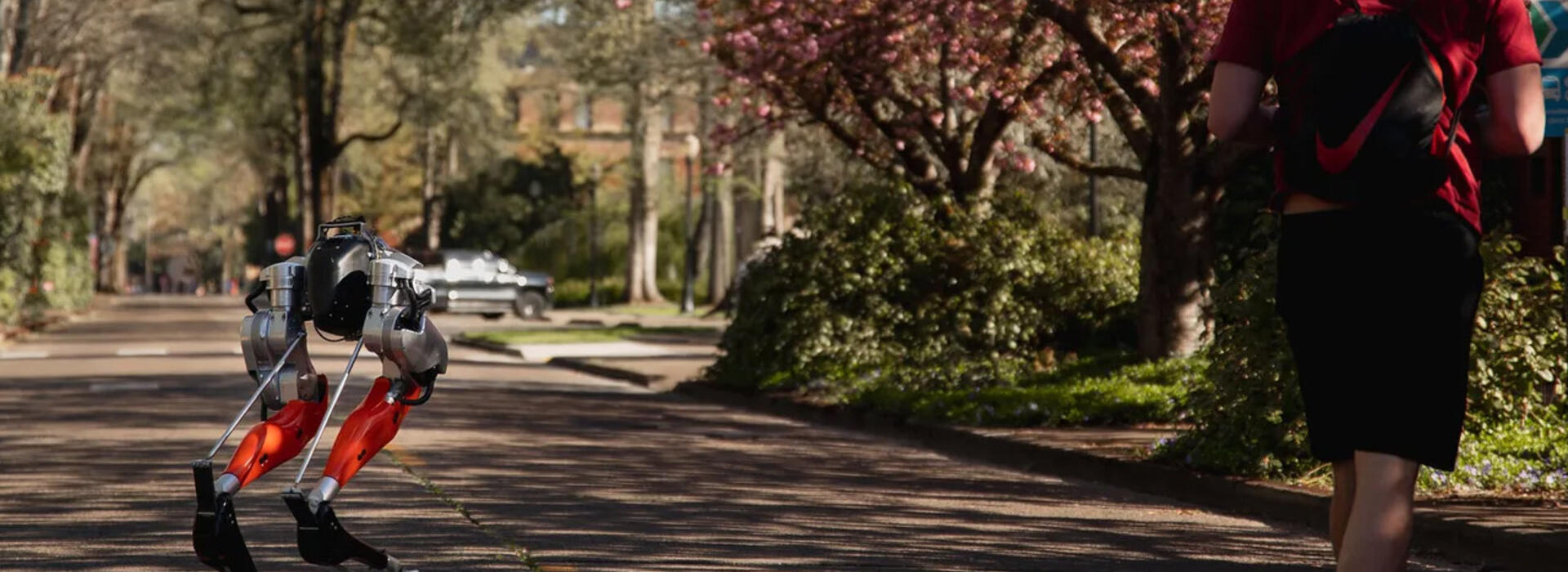 Student controls Cassie, a bipedal robot, on a campus road. 