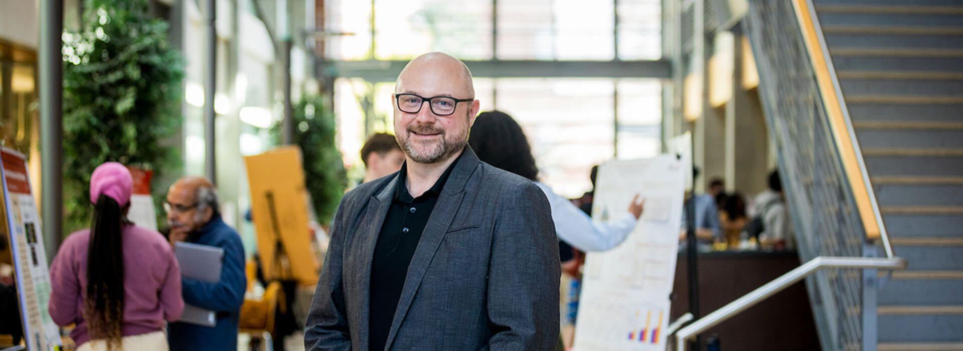 David Zier poses in Kelley Engineering Center atrium with presenters and posters in the background.
