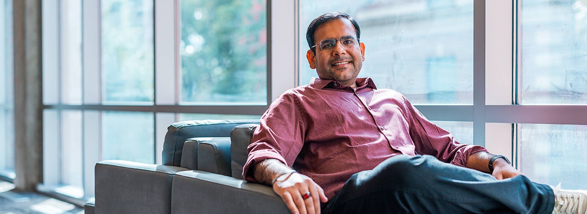 Manish Motwani sits smiling in a chair by the windows of Kelley Engineering.