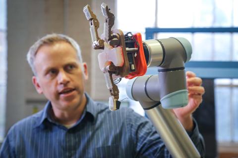 Joe Davidson holding a robotic hand.