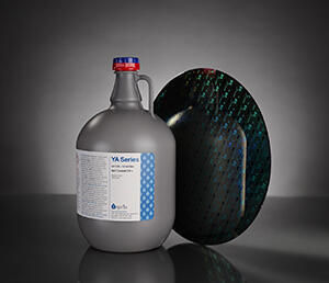 Jug of Inpria's inorganic photoresist solution beside a reflective wafer.