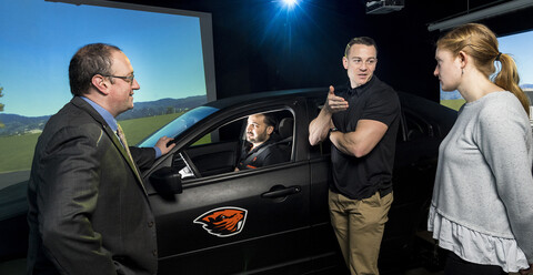 Civil engineering professor David Hurwitz having a conversation next to the Driving and Bicycling Simulator.