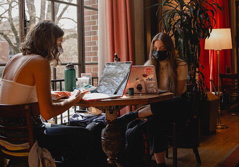Two students sitting a coffee table and working.